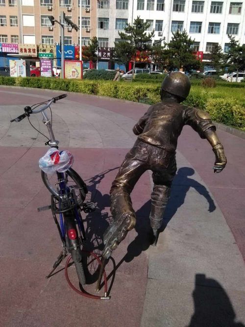 乌兰浩特市五一广场，游客将自行车与雕塑锁在一起